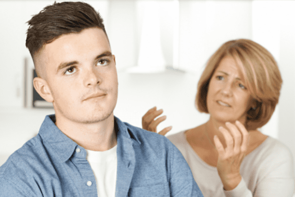 Woman is exasperated with her son in the foreground who looks annoyed. When you're thinking, "I hate my son's girlfriend!" that's not what he understands from your behavior. 