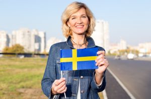 best place for a single woman to live in the world header featuring a woman holding the Swedish flag.
