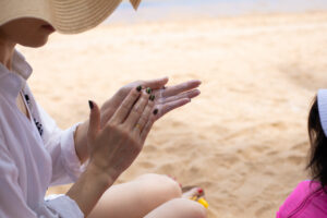 Woman in a Straw Hat Applying Sunscreen at the Beach
