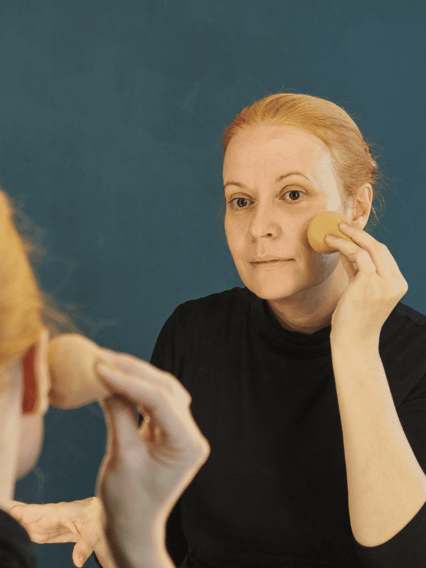 Woman applying a BB cream to her face with a sponge. 
