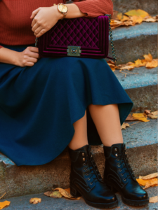 A woman wearing chunky ankle boots over 40 with a feminine skirt.