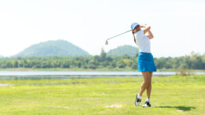 A woman in some of the best golf clothing for women driving on the green.