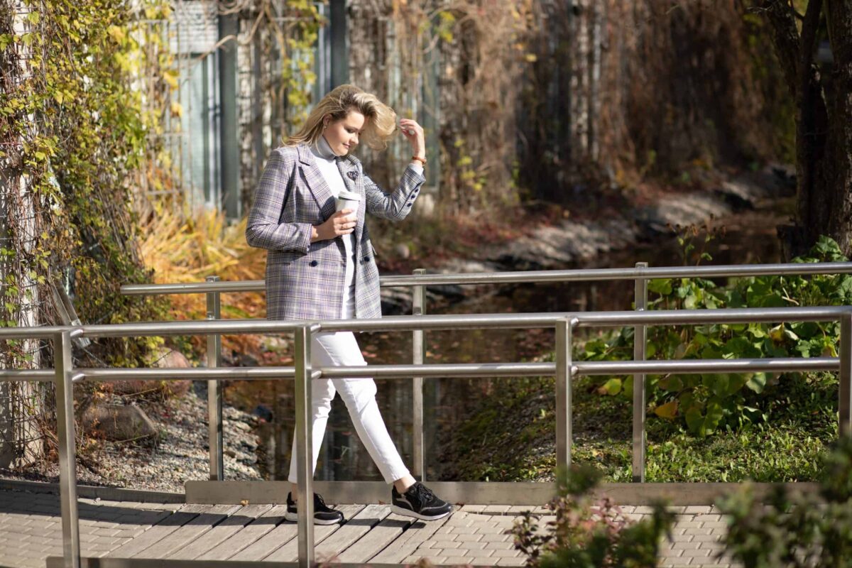 Woman styling one of our picks for best equestrian fashion: a plaid blazer and white skinny jeans.