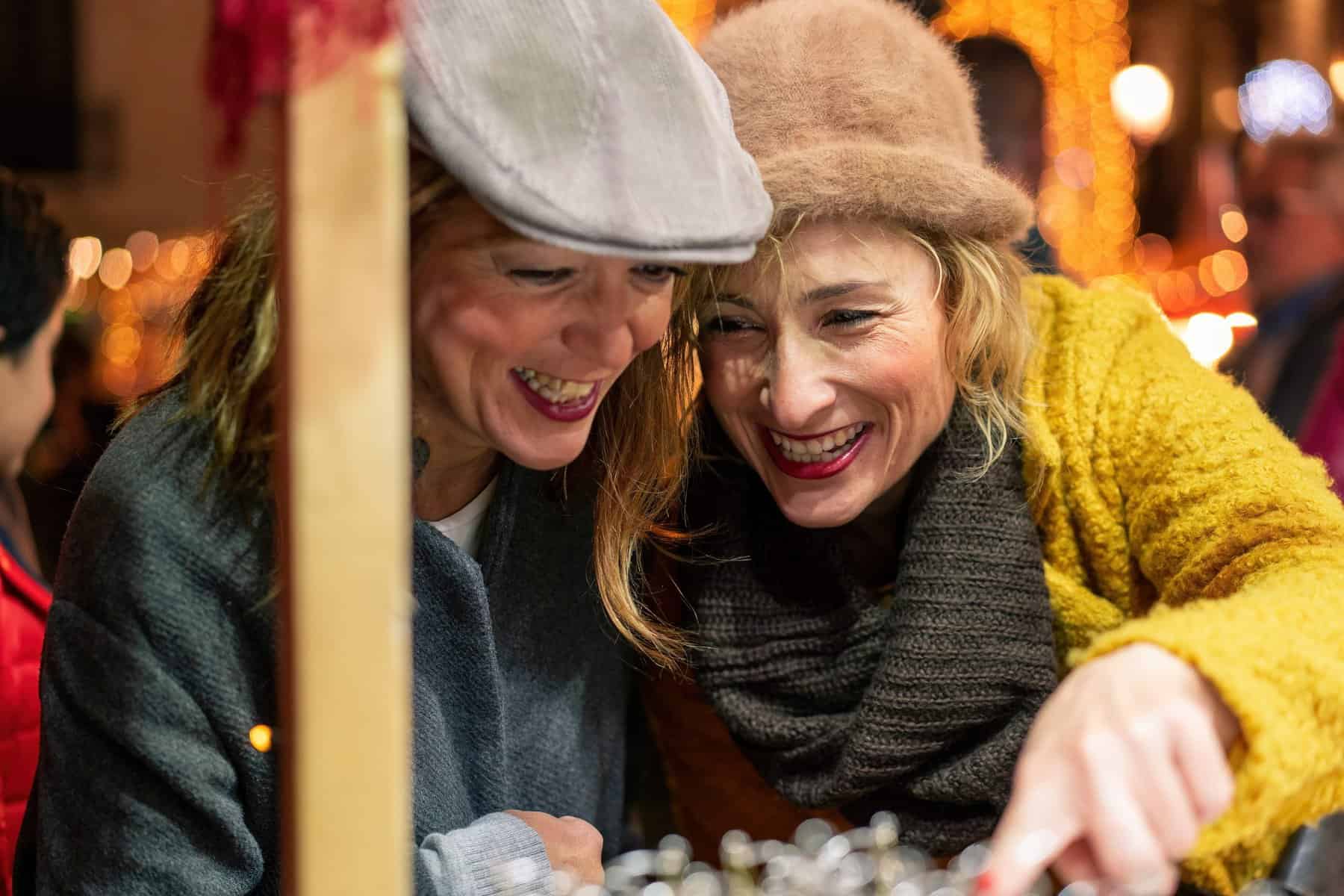 Two woman celebrating a Christmas tradition. They are smiling and laughing.