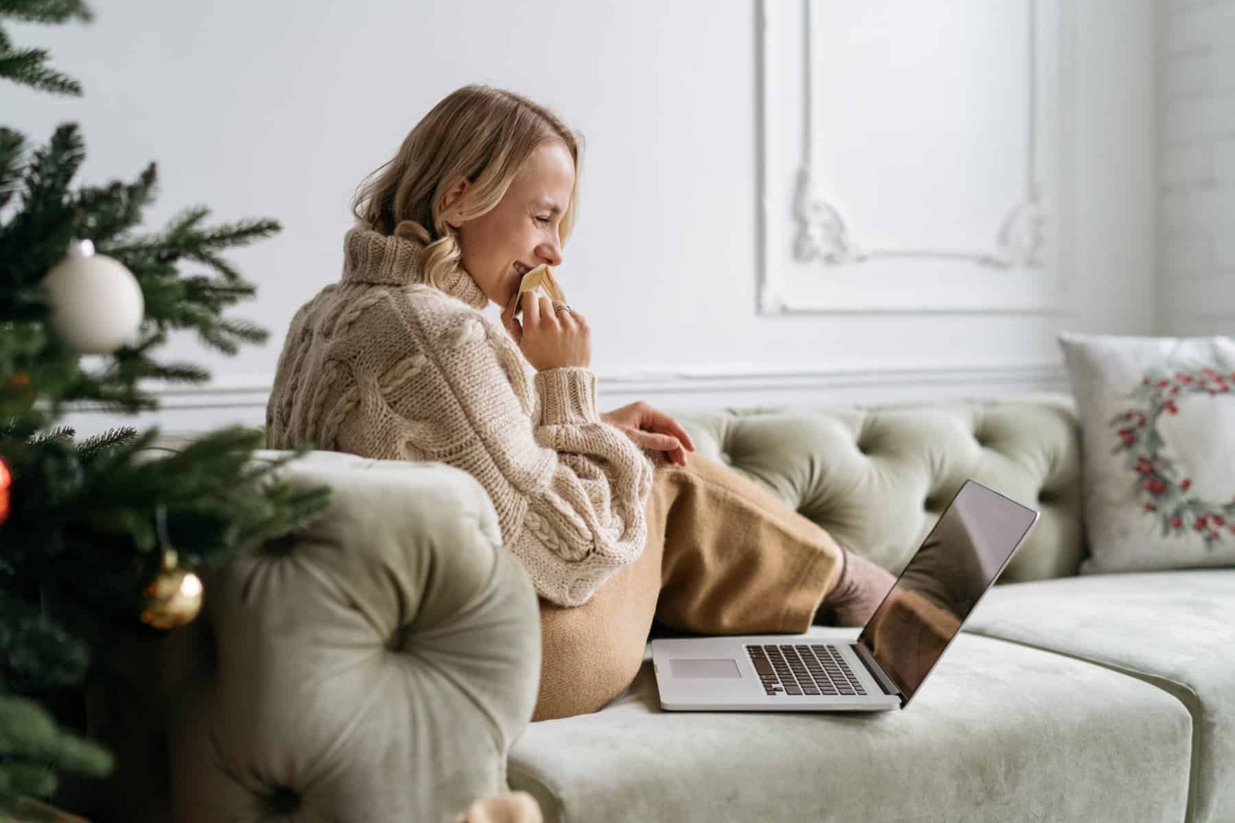 Woman watching holiday romantic comedies on her laptop on couch.
