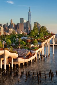 Little Island Park in New York City has a series of elevated platforms over the Hudson River with a view of the cityscape.