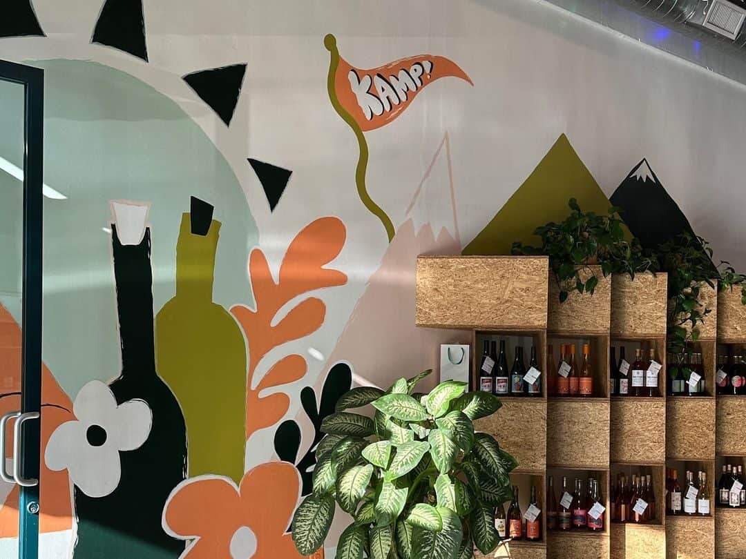 KAMP's walls are decorated with a playful mural and wine bottles fill their shelves. 