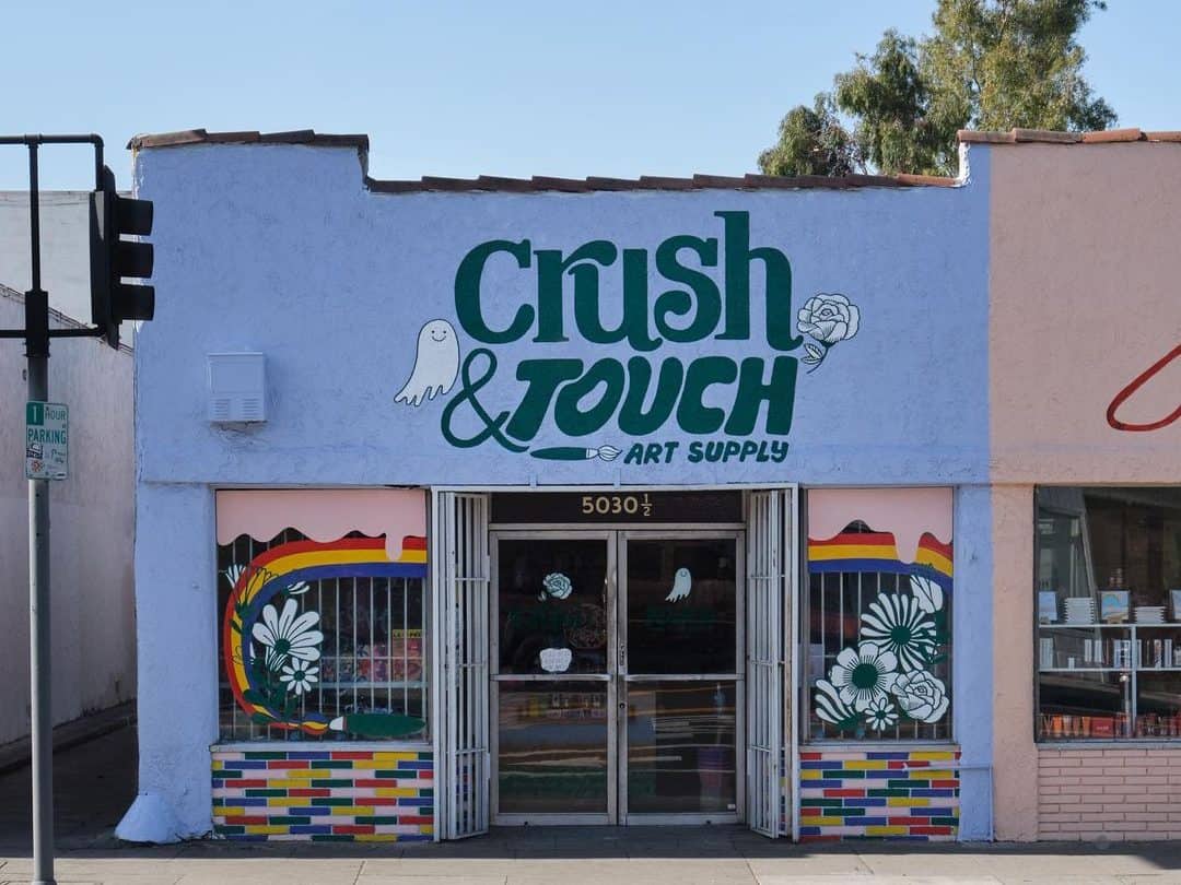 Crush & Touch's storefront features colorful window murals with a rainbow and flowers and a handpainted building facade. 