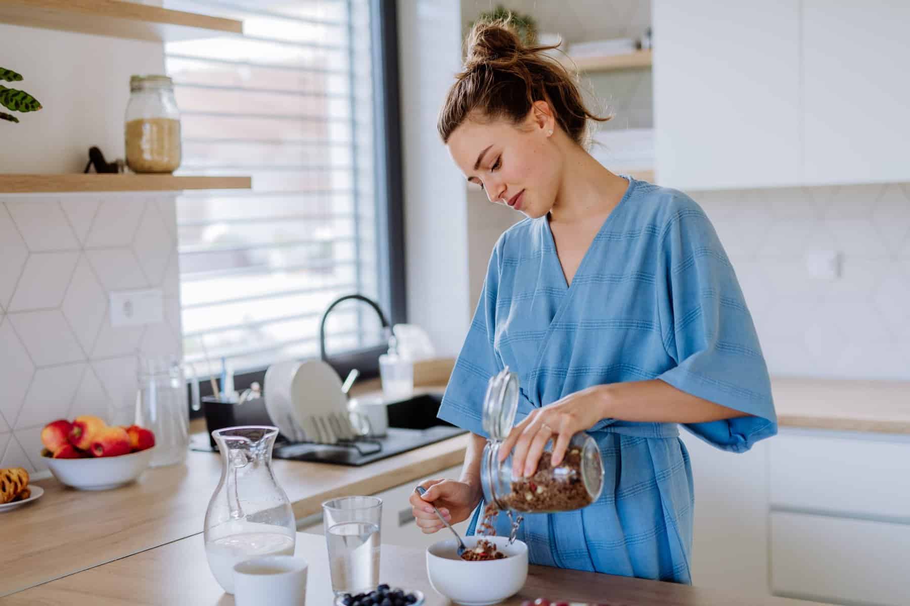 A woman pours whole-grain granola into a bowl as part of her MIND diet breakfast.