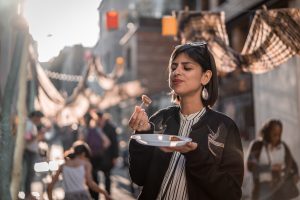 Woman enjoys food in the street.