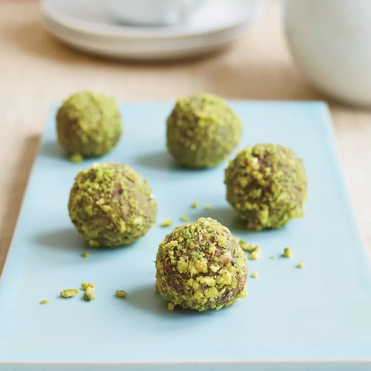 A close-up showing the texture of the crushed pistachio coating of these date bonbons. 