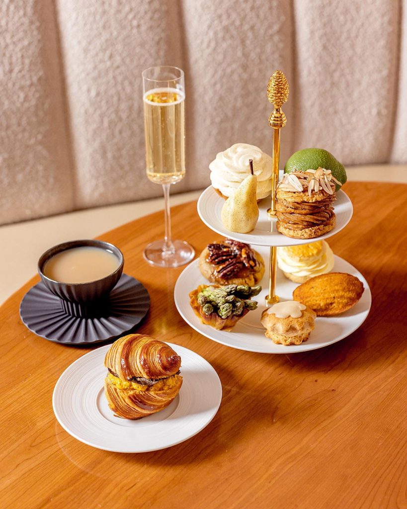 A tabletop with tea, champagne, and tower of patisserie desserts. 
