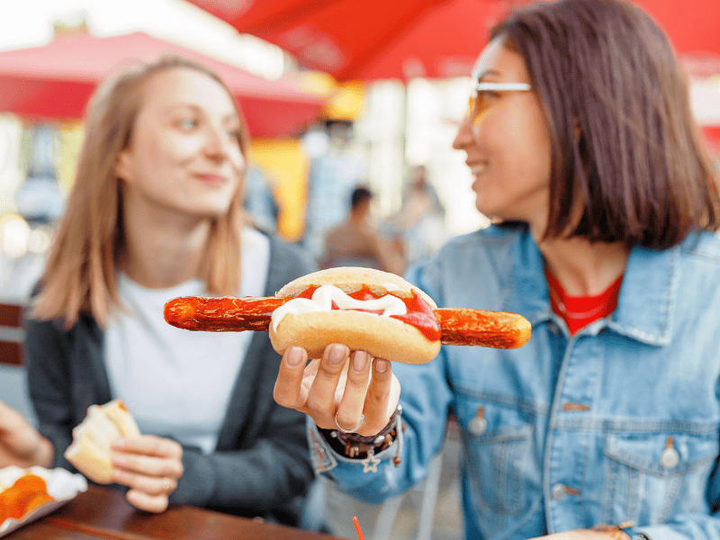 Woman with a currywurst in a bun.
