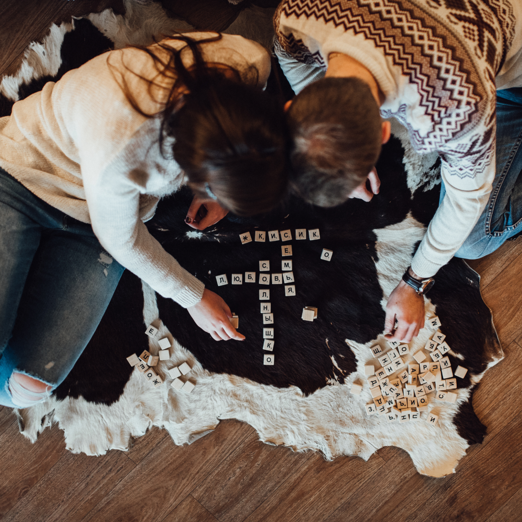 A couple looks down at game tiles on the rug as part of their Valentine's Day date. 