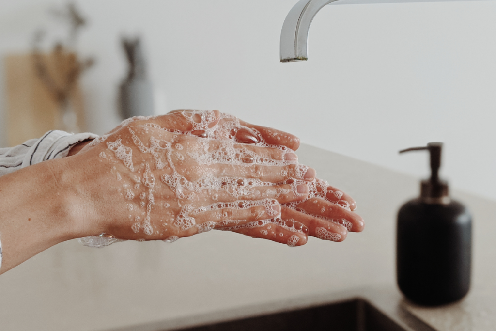 A close-up of a woman washing her hands, which can strip the skin's moisture and cause dry skin on hands. 