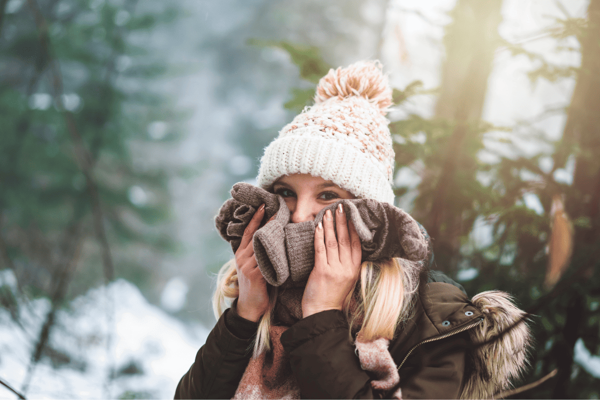 Woman holds her hands to her cheeks in the cold. She's protecting her skin from dry winter air.